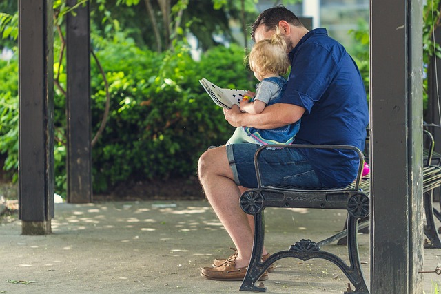 Man sitting on bench reading to child
